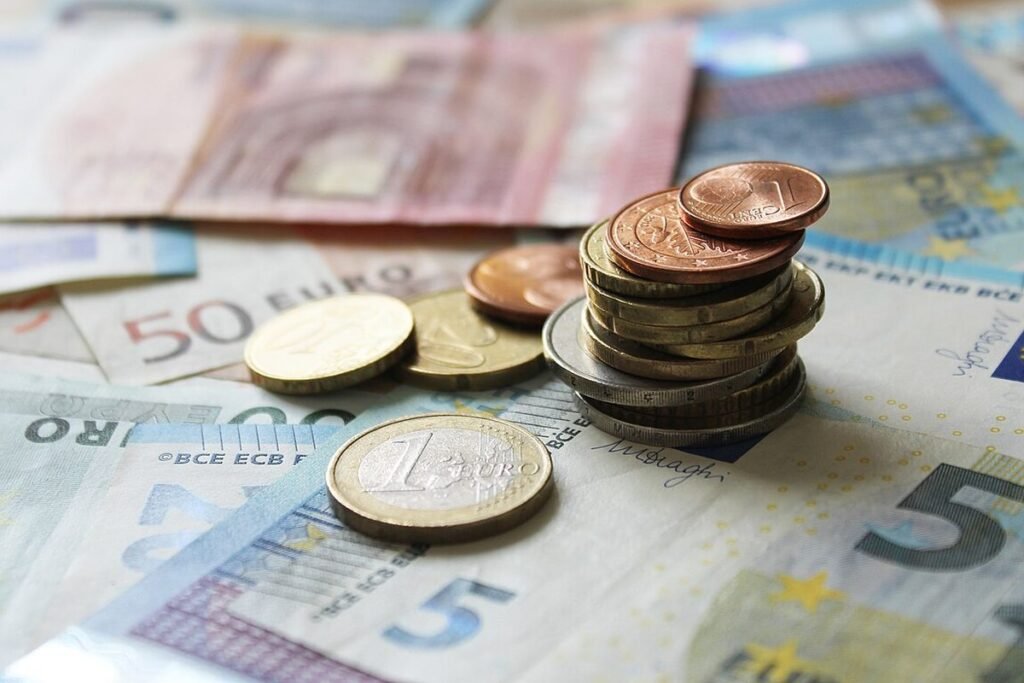 Pièces en euros empilées sur des billets de 5, 10, 20 et 50 euros