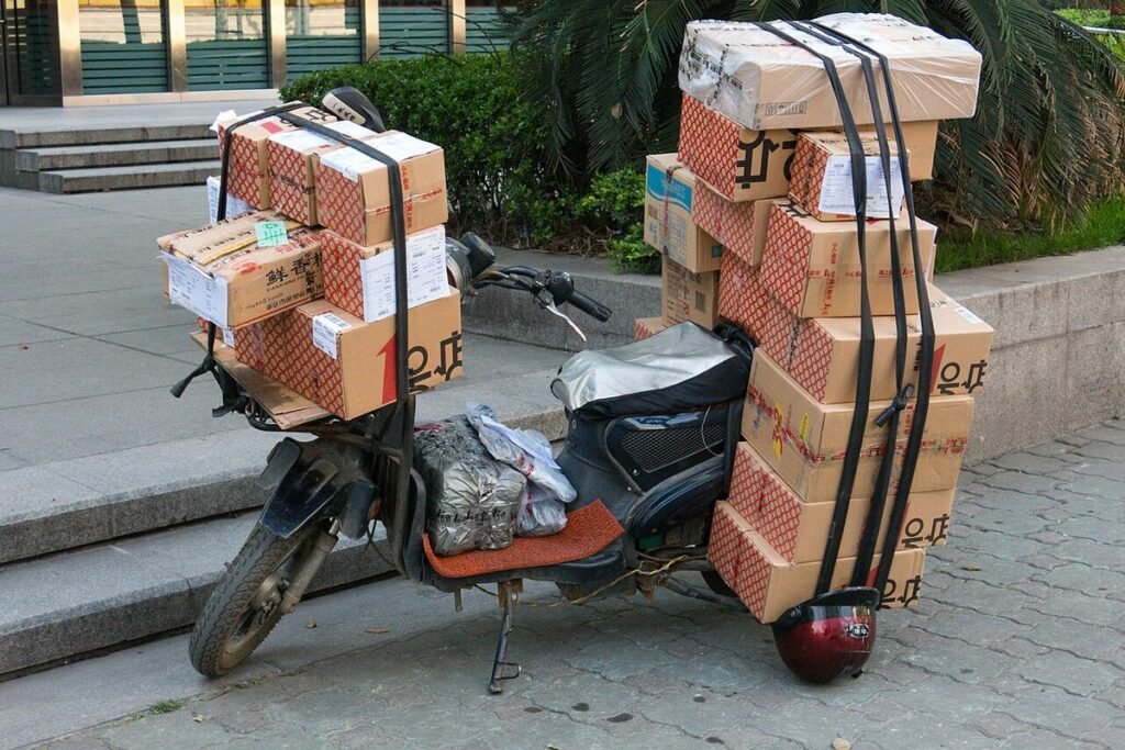 Scooter électrique chargé de dizaines de cartons de livraison sanglés, garé sur un trottoir en Chine